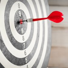 Red dart arrow hitting in the target center of dartboard Red dart arrow hitting in the target center of dartboard